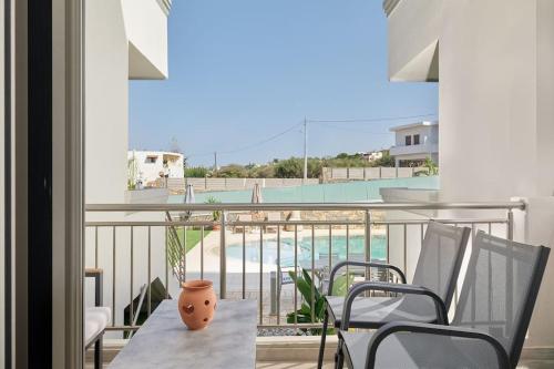 a balcony with a table and chairs and a pool at Modern Family apartment Ewa with pool, dining area on Crete coast in Stavromenos