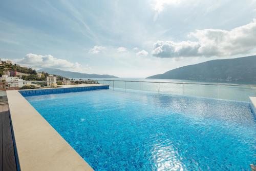 een groot zwembad met uitzicht op het water bij Garni Hotel Kruso in Herceg-Novi