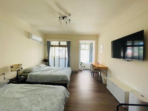 um quarto com 2 camas, uma secretária e uma televisão em Hongqiao Inn 桃園市民宿編號136號 em Longtan