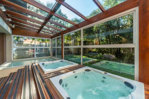 a jacuzzi tub in a room with large windows at Hotel Laghetto Stilo Borges in Gramado