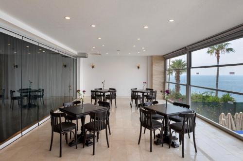a dining room with tables and chairs and the ocean at Ramada Plaza Antalya in Antalya