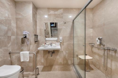 a bathroom with a shower and a toilet and a sink at Ramada Plaza Antalya in Antalya