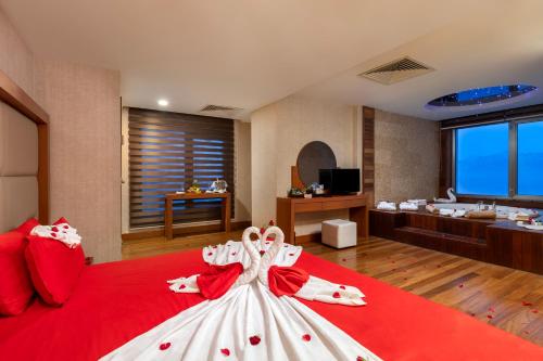 a large bedroom with a red bed with a red and white dress at Ramada Plaza Antalya in Antalya