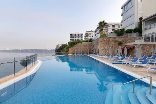 einen Pool mit Liegestühlen und Wasser in der Unterkunft Ramada Plaza Antalya in Antalya