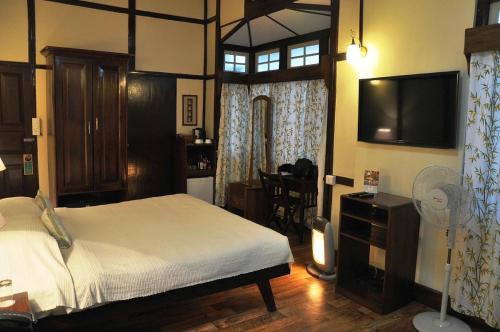 a bedroom with a bed and a flat screen tv at Cafe Shillong Bed and Breakfast in Shillong
