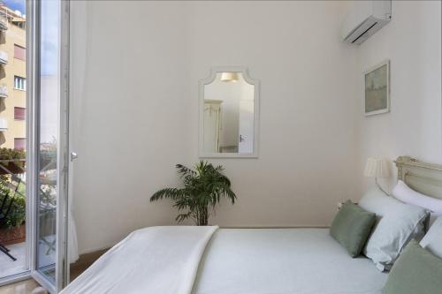 a white bedroom with a bed and a mirror at Le case di Frelli in Palermo