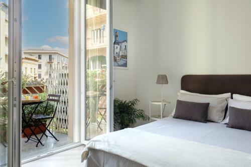a white bedroom with a bed and a balcony at Le case di Frelli in Palermo