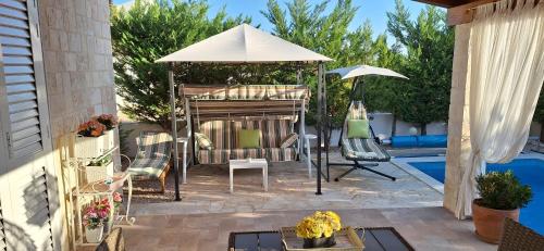 a patio with an umbrella and chairs next to a pool at Villa Susann in Šibenik