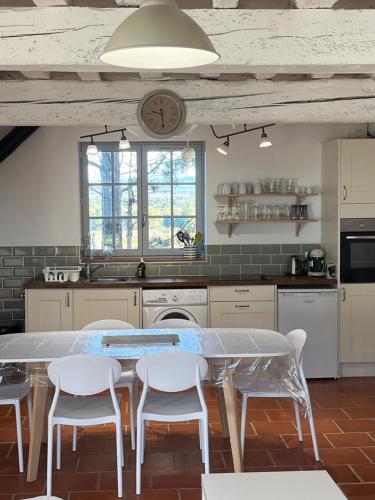 a kitchen with a table and chairs and a clock at Domaine Saladry in Villepinte