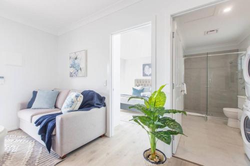 雷德克利夫'Redcliffe Retreat' Moreton Bay Coastal Cottage的带沙发的白色客厅和浴室