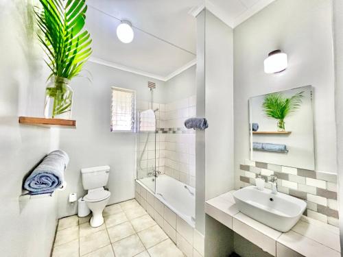 a bathroom with a sink and a toilet and a bath tub at St Lucia Holiday Cottage in St Lucia