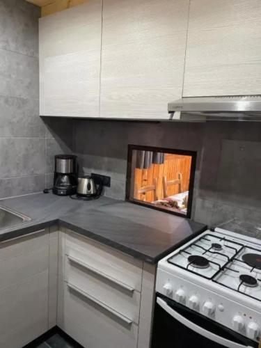 Il comprend une cuisine équipée d'une cuisinière et de placards blancs. dans l'établissement Le Génépi, à La Plagne Tarentaise