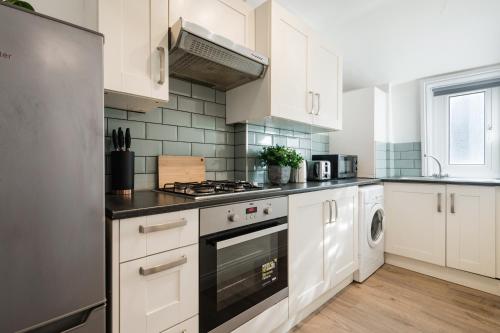 a kitchen with white cabinets and a stove top oven at London Paddington Station Apartments in London