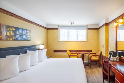 a hotel room with a bed and a table and chairs at Les Suites de Laviolette, an Ascend Collection Hotel in Trois-Rivières