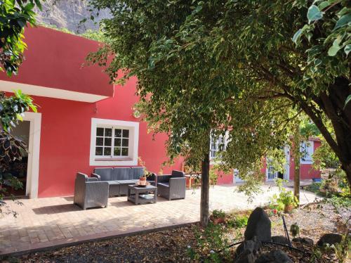 un edificio rojo con sillas y una mesa frente a él en La Casita, en Agulo