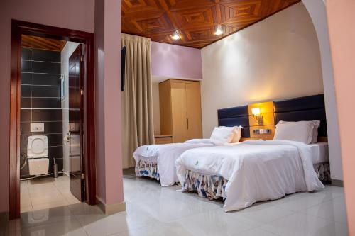 HOTEL MICKEL في دوالا: غرفة في الفندق بسريرين وممشى في الحمام