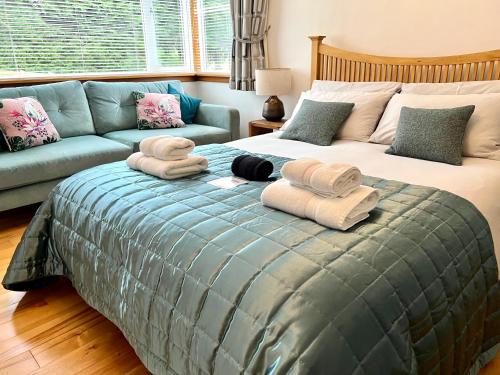 a bedroom with a bed with towels and a couch at The Annexe at Cluny House in Inverness
