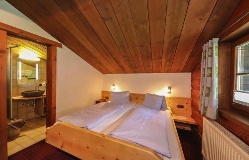 a bed in a room with a wooden ceiling at Pension Hochwart Hof in Saalbach-Hinterglemm