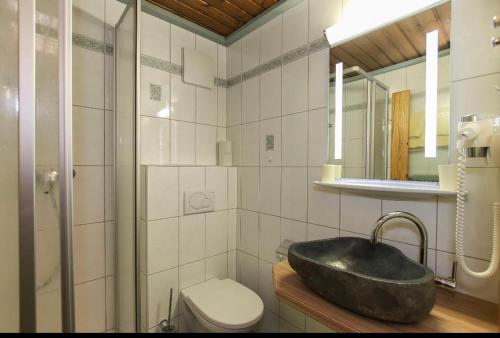 a bathroom with a black sink and a toilet at Pension Hochwart Hof in Saalbach-Hinterglemm