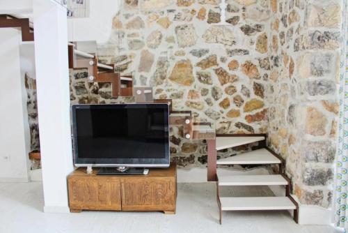 een televisie op een houten standaard voor een stenen muur bij Golden rooms in Castellammare di Stabia