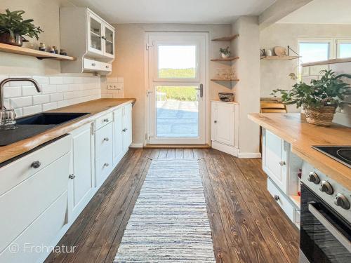 a kitchen with white cabinets and a wooden floor at Tolles Ferienhaus Frohnatur mit Sauna in ruhiger Lage in Plauen