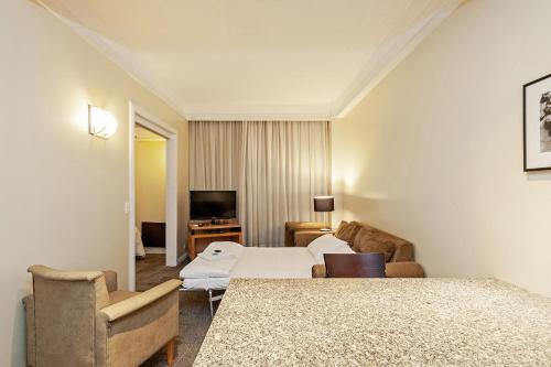 Habitación de hotel con cama y TV en Slaviero Curitiba Shopping en Curitiba