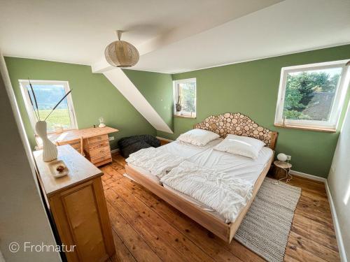a bedroom with a bed and a table and two windows at Tolles Ferienhaus Frohnatur mit Sauna in ruhiger Lage in Plauen
