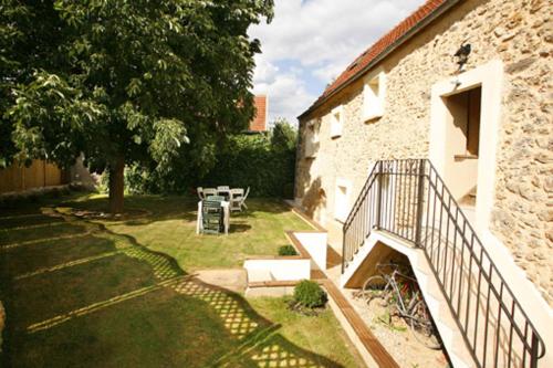 un jardin avec une table et un escalier à côté d'un bâtiment dans l'établissement S2-gite sevin, à Saint-Forget