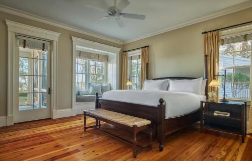 a bedroom with a bed and a bench and windows at Montage Palmetto Bluff in Bluffton