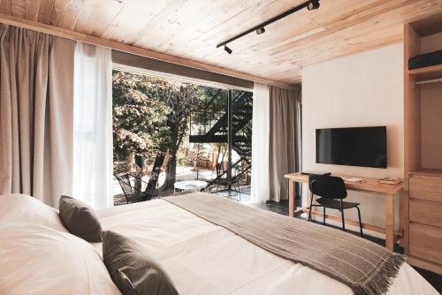 a bedroom with a bed and a desk and a television at Villa Sofía Apart Hotel & Spa in San Carlos de Bariloche