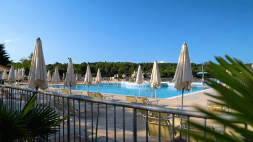 a swimming pool with white umbrellas and chairs and tables at Easyatent Mobile home Bijela Uvala in Poreč