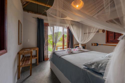 a bedroom with a bed with a canopy and a window at Chalé Vera Ar condicionado Pousada 35knots Brasil in Luis Correia