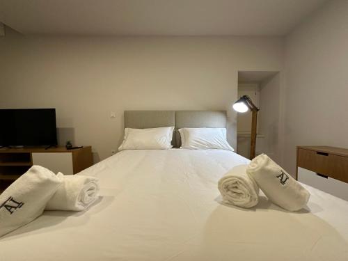 ein Schlafzimmer mit einem großen weißen Bett mit Handtüchern darauf in der Unterkunft SM APARTMENTS in Porto