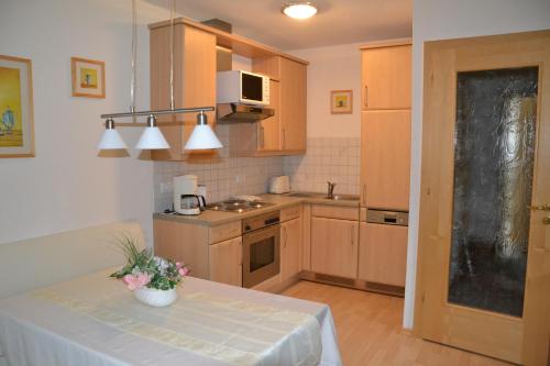 eine Küche mit einem Tisch und einer Blumenvase darauf in der Unterkunft Haus Alpin Apartments in Pettneu am Arlberg
