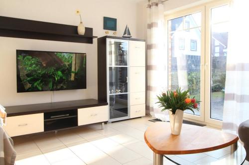 ein Wohnzimmer mit einem TV und einem Tisch in der Unterkunft Dünenhäuser Haus 3 in Boltenhagen