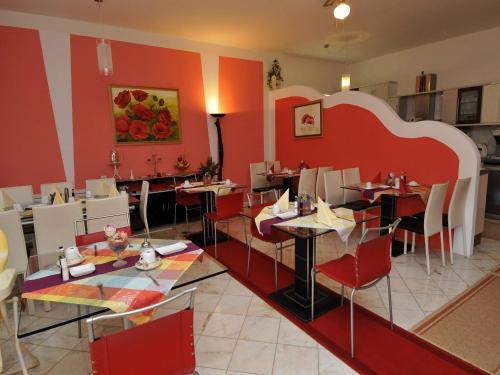 a restaurant with red walls and tables and chairs at Hotel Haus Am Meer Cavtat in Cavtat