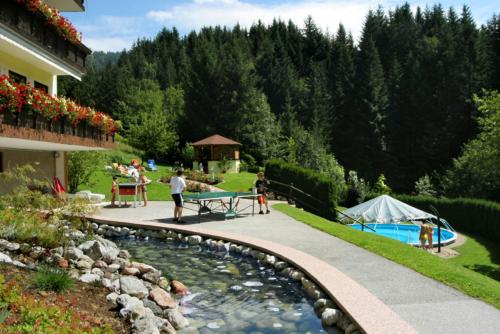 eine Gruppe von Menschen, die um einen Teich im Hof stehen in der Unterkunft Alpenapartments Unterschlag in Annaberg im Lammertal