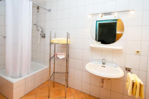 a bathroom with a sink and a tub and a mirror at Gästehaus beim Schneidersepp in Ruhpolding