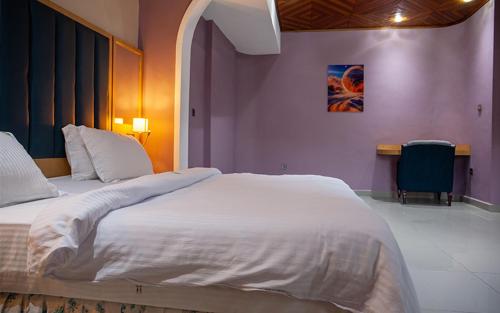 a large white bed in a room with a table at HOTEL MICKEL in Douala