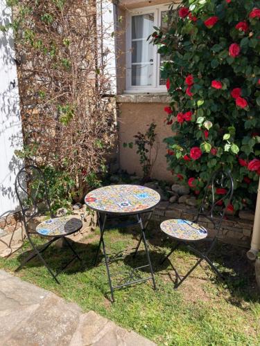 a table and two chairs in a yard with roses at Chez Liselotte in Borgo