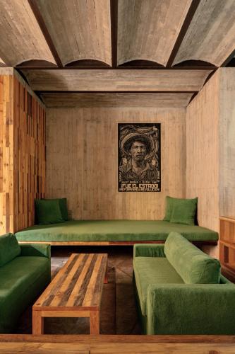 a living room with green couches and a table at Otro Oaxaca, a Member of Design Hotels in Oaxaca City