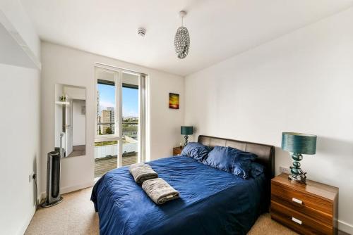 a bedroom with a blue bed and a window at Amazing 2 bed 2 bath flat in Canary Wharf in London
