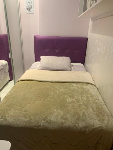 a bed with a purple headboard in a room at Tropical executive in Manaus