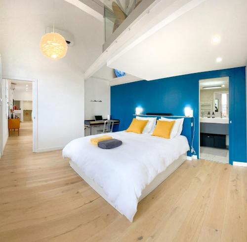 ein Schlafzimmer mit einem großen weißen Bett und einer blauen Wand in der Unterkunft Le Filatiers - incroyable loft aux Carmes in Toulouse