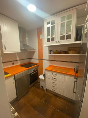 una piccola cucina con armadi bianchi e ripiani arancioni di Chamartin De frente a 4 torres a Madrid