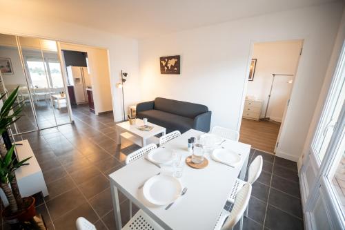 ein Wohnzimmer mit einem weißen Tisch und Stühlen in der Unterkunft ROBESPIERRE - Tout équipé & Calme - TV et WIFI in Saint-Étienne