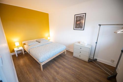 a bedroom with a bed and a yellow wall at ROBESPIERRE - Tout équipé & Calme - TV et WIFI in Saint-Étienne