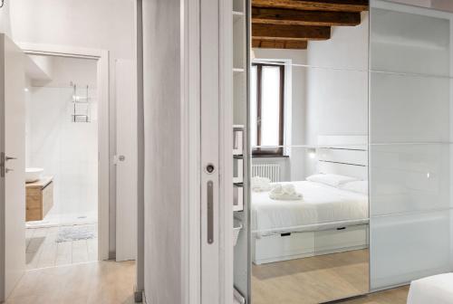 a white bedroom with a bed and a glass wall at Flats4Rent Irene in Verona