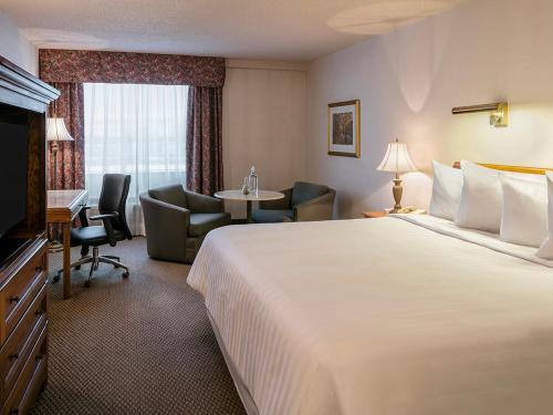 a hotel room with a large bed and a desk at Hôtels Gouverneur Montréal - Île Charron in Longueuil