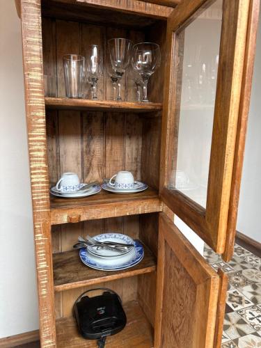 um armário de madeira com pratos e copos de vinho em Nosso Chalet em Lavras Novas